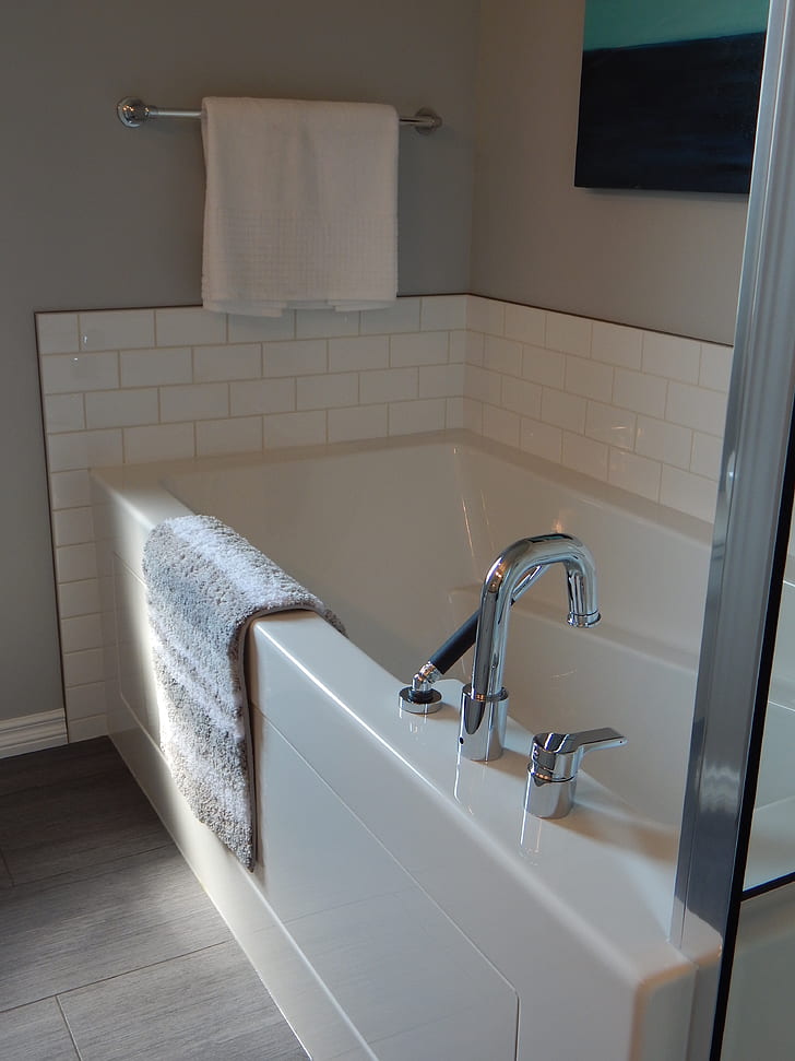 white ceramic bathtub with white towel hanged on silver towel bar