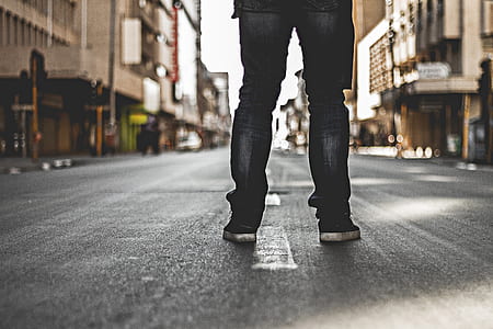 person in black jeans standing on road