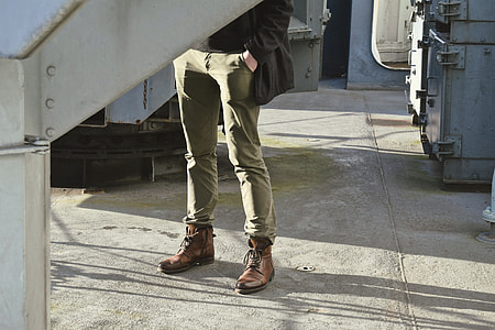 man standing wearing green jeans and brown shoes