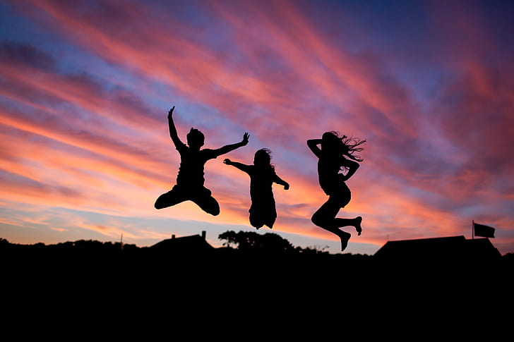 silhouette of three people jumping during sunset