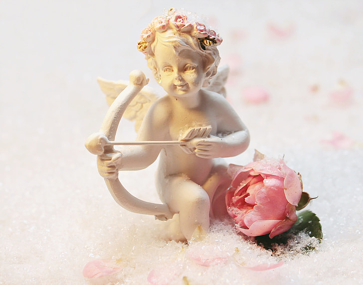 selective focus photography of white marble cupid figurine with pink rose