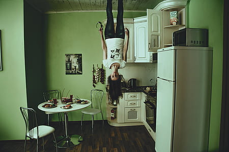 woman standing on ceiling beside white top-mount refrigerator in house