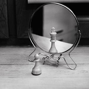 Grayscale Photo of Reversible Mirror in Front of Chess Piece