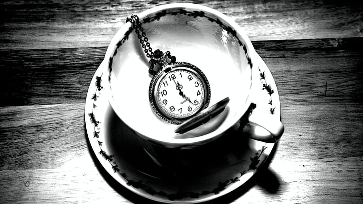 grayscale photo of pocket watch on teacup with saucer