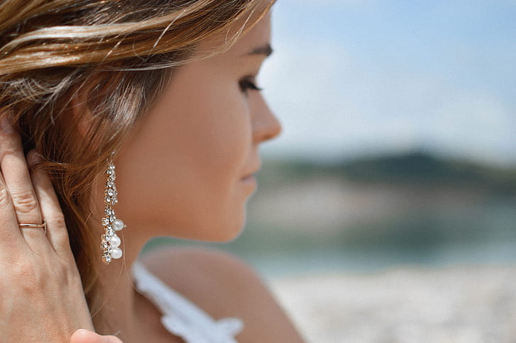 shallow focus photography of woman wearing white top and dangle earring