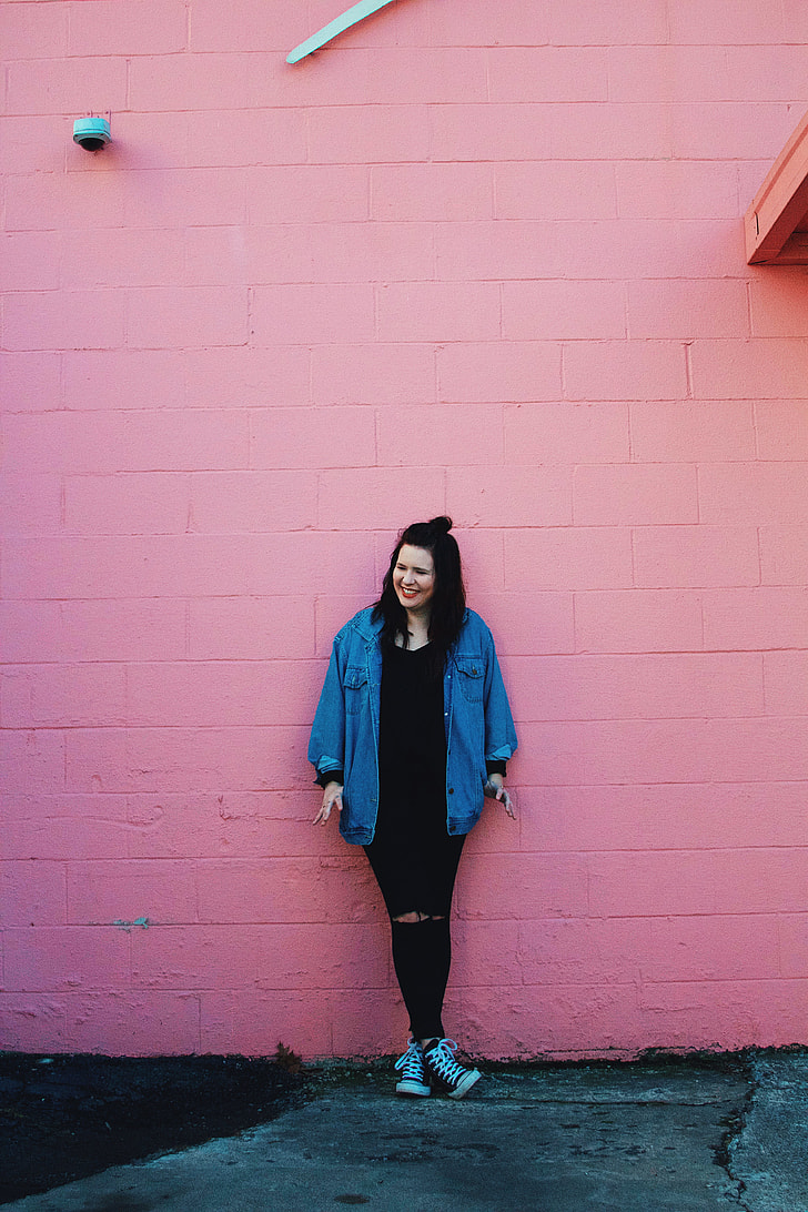 woman leaning on pink concrete painted wall