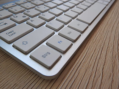 White Computer Keyboard on Brown Wooden Table