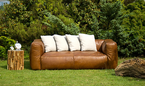 brown leather couch with four white throw pillows on top
