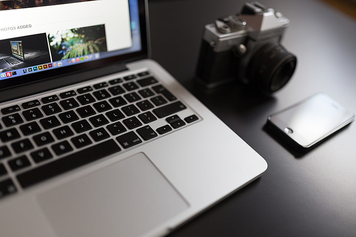 gray MacBook beside of DSLR camera