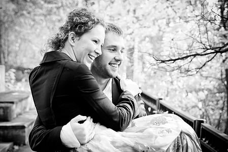 grayscale photography of man carrying woman while smiling