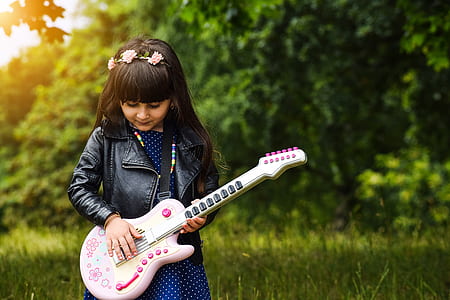 shallow focus photography of girl holding guitar