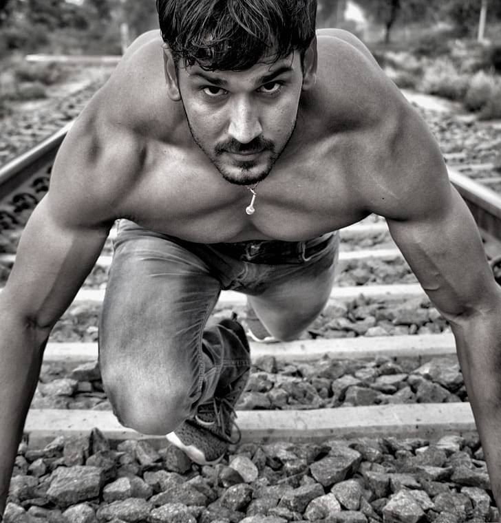 man wearing jeans standing on train tracks