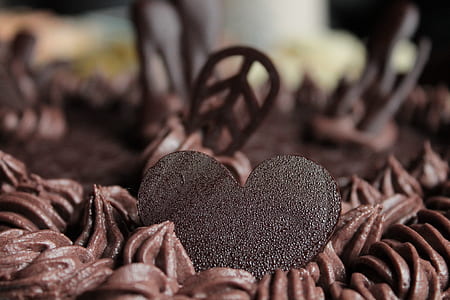 closeup photography of chocolate heart toppings on chocolate icing-covered cake