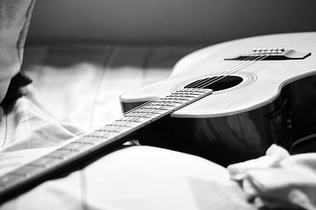 Gray Scale Photography of Acoustic Guitar on Bed