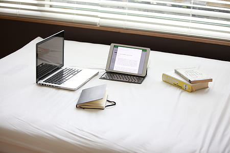 Macbook Pro over White Fabric Sheet Beside White Ipad