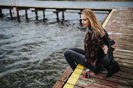 Beautiful blonde woman on a wooden pier by the lake
