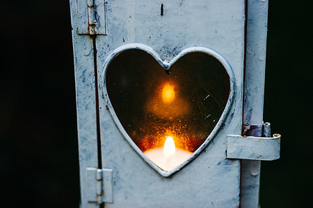 candle reflected on heart mirror with white frame