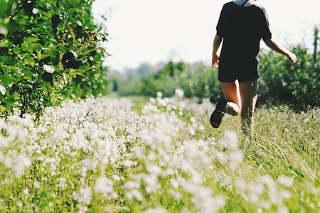 woman wearing black top and black short shorts walking on green grass field