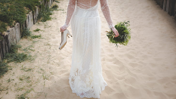 woman in wedding gown walking on sand