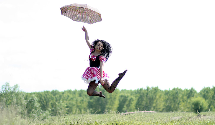 woman holding umbrella wearing polka dot dress on grass field