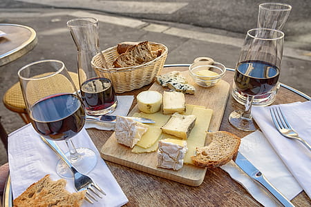 clear short-stemmed wine glasses, sliced breads, brown wooden chopping board, and brown wicker basket on brown wooden table