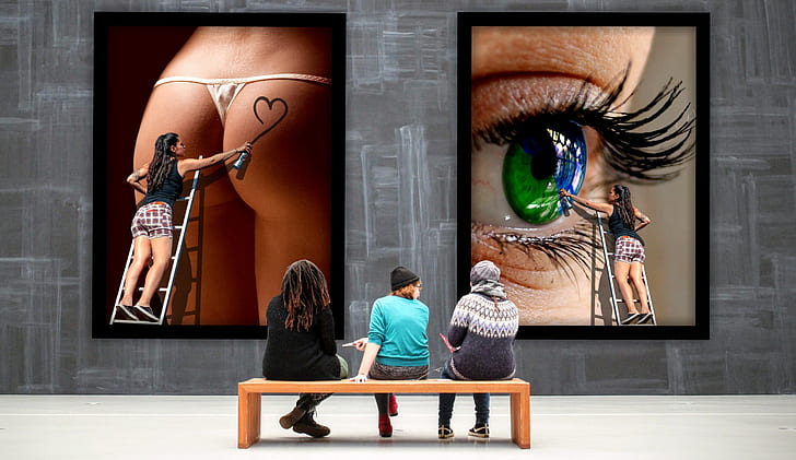 three people sitting on wooden bench in front of two artworks