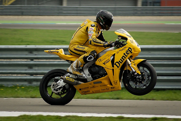 man wearing black full-face helmet riding yellow naked motorcycle