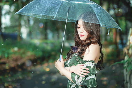 woman holding clear shade umbrella standing in shallow photography