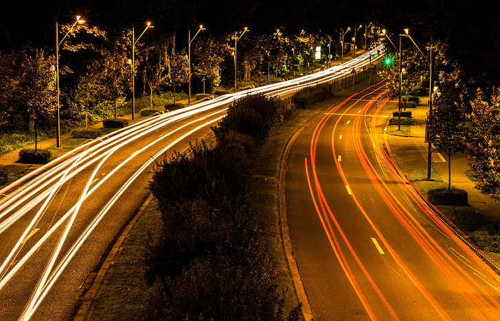 timelapse photography of passing cars in two highways with center isle during nighttime