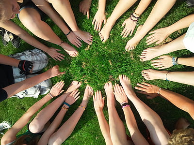 people hands and feet on green grass