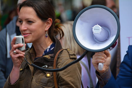 woman in brown jacket holding megaphone during daytime