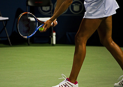 woman wearing white skirt and pair of white sneakers holding tennis racket