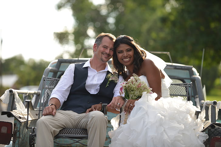 bride and groom riding the back of a truck during daytime