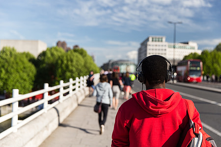 A man wearing headphones walks along a bridge over the River Thames on a sunny day in Central London. This image was captured using a Canon 6D DSLR