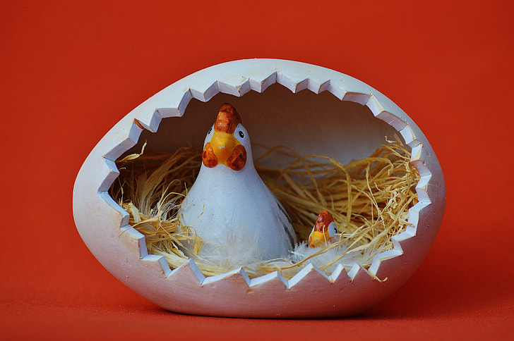 two white-and-red hens inside egg nest figurine
