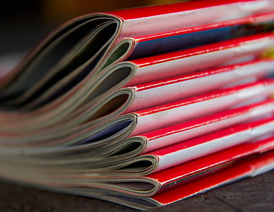 selective focus photography piled red magazine books