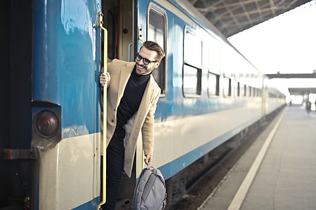 man wearing beige 2-button suit jacket holding gray backpack