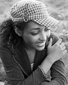 smiling woman wearing denim notched lapel jacket and houndstooth cap
