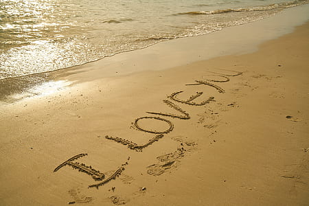 photo of I Love You text written on sand in seashore