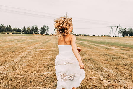 woman in white strapless gown running on brown field