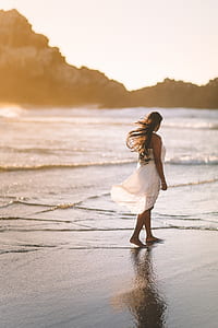 woman wearing white dress walking on beach