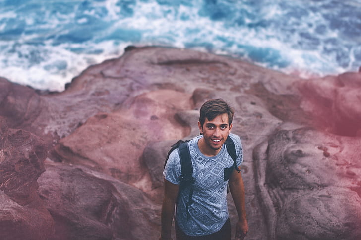 Photo Of Man Wearing Blue Shirt And Backpack Near Ocean