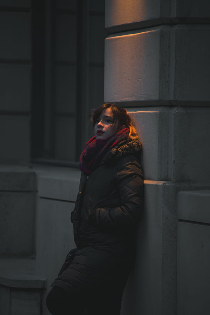 woman leaning on wall during nighttime