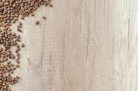roasted brown coffee beans scattered on brown wooden surface