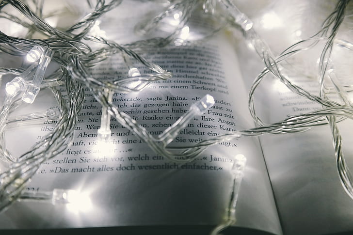 photography of turned on white string lights on opened book page
