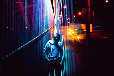 man wearing gray pullover hoodie on dark street with red lights