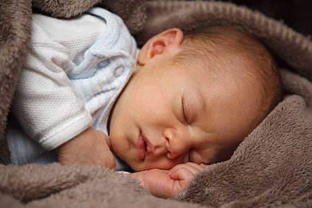 baby wearing white long-sleeved shirt sleeping on brown fleece sleep sack