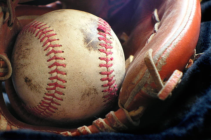 white and red baseball with brown leather baseball glove