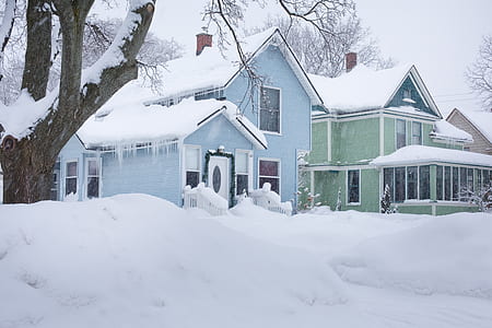 two green and blue house covered with snow during winter