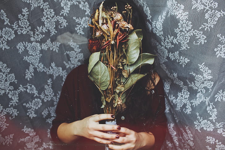 photography of woman covering her face with flowers
